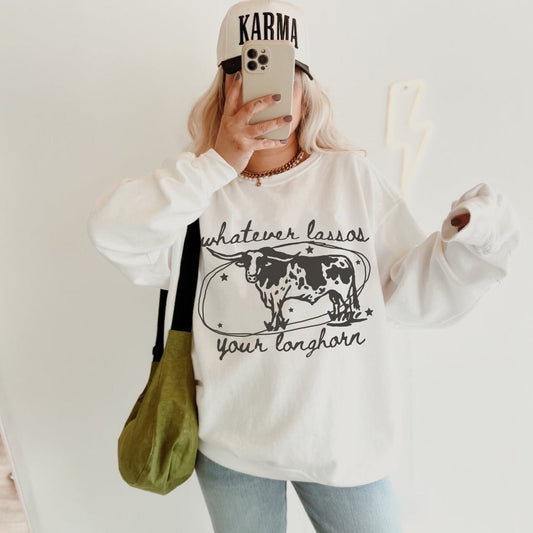 Long sleeve, oversize unisex fit Gildan sweatshirt in sport grey with a longhorn cow getting lasso’d and the quote whatever lasso’s your longhorn.